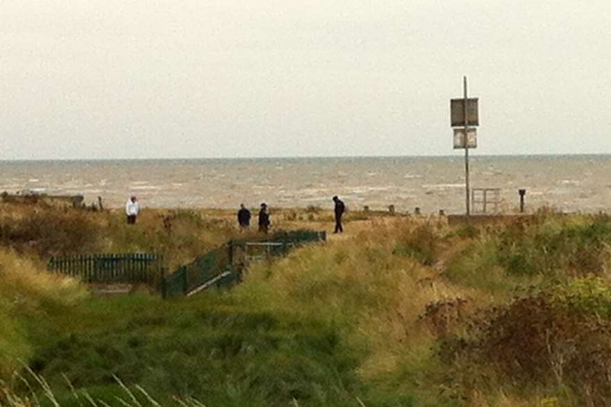 A team of police officers cordon off the other end of a Leysdown beach where the body was found