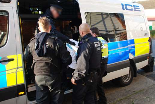 Police put a suspect in a van during the operation