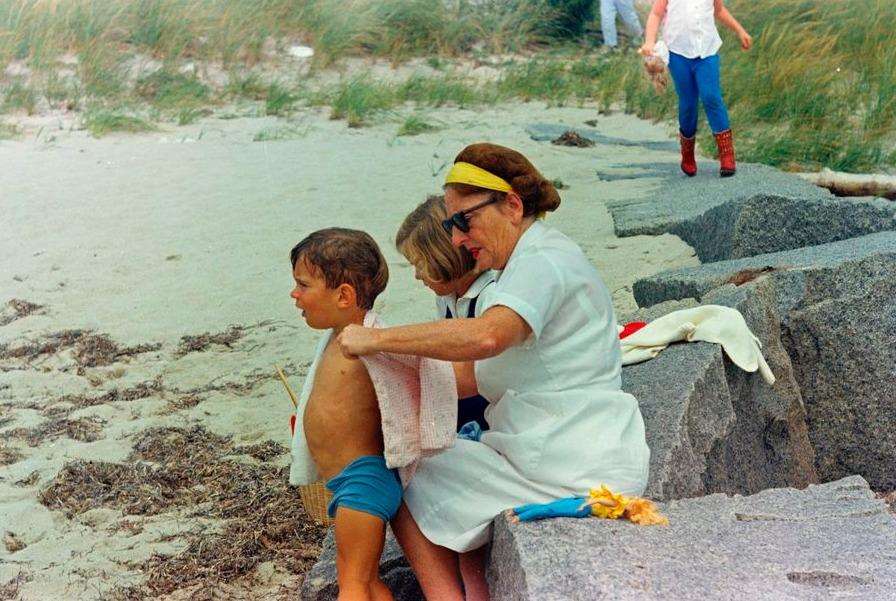 Maud Shaw helps John F. Kennedy Jr., put on a shirt on the beach in Hyannis Port, Massachusetts