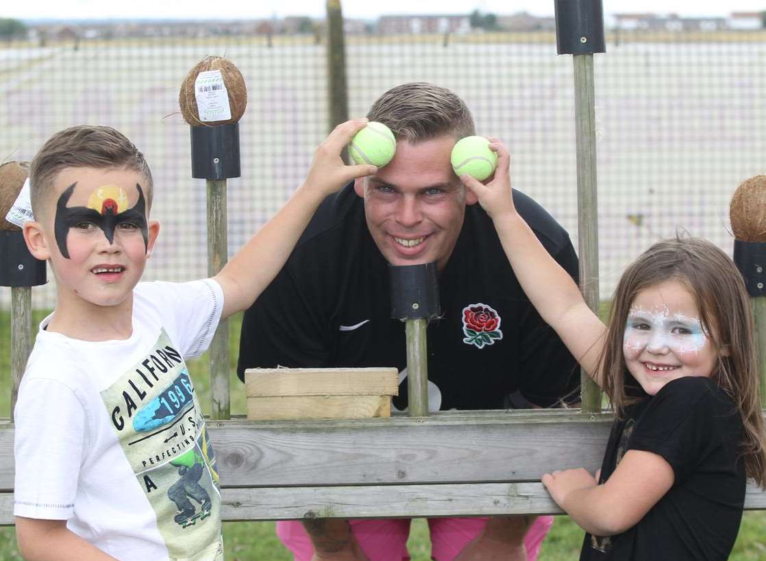 Oliver Gold-Smith, seven, and his sister Maisey, six, with Pete Watson at the coconut shy