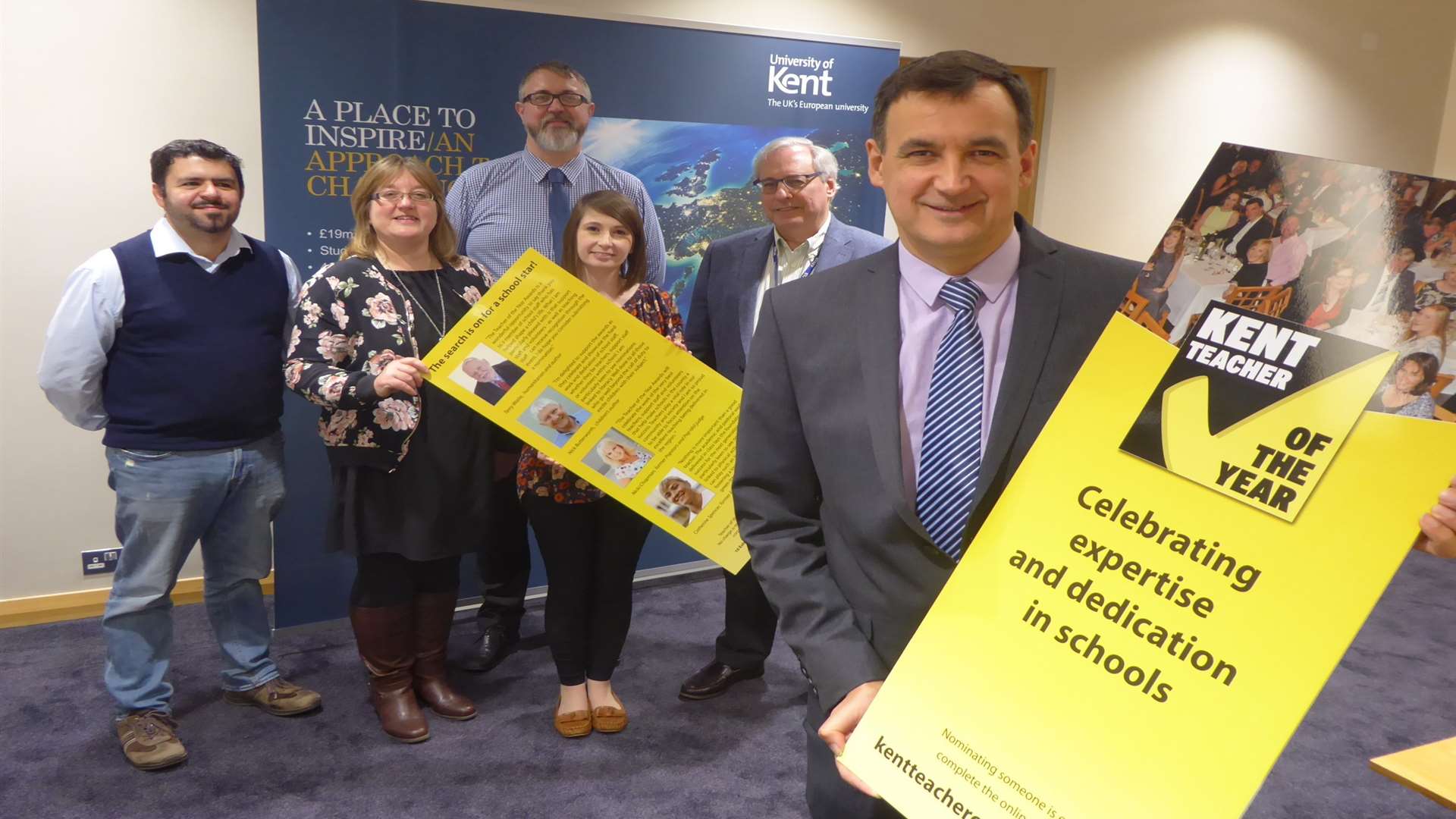 Steven Holdcroft, Assistant Director of Enrolment Management Services at the University of Kent, joins staff to unveil the Kent Teacher of the Year Awards celebrity flyer that will be used to promote the 2018 event.
