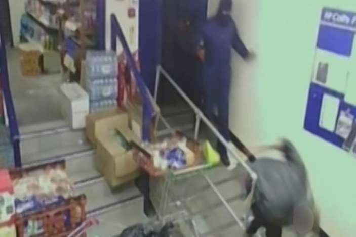 A worker is pushed by a raider in one of the McColl's robberies