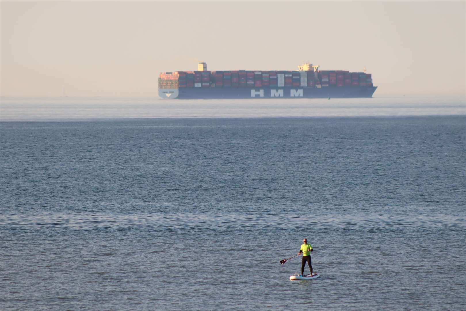 The world's biggest container ship HMM Algeciras off Minster beach, Sheppey, with a paddle-boarder. Picture: John Nurden