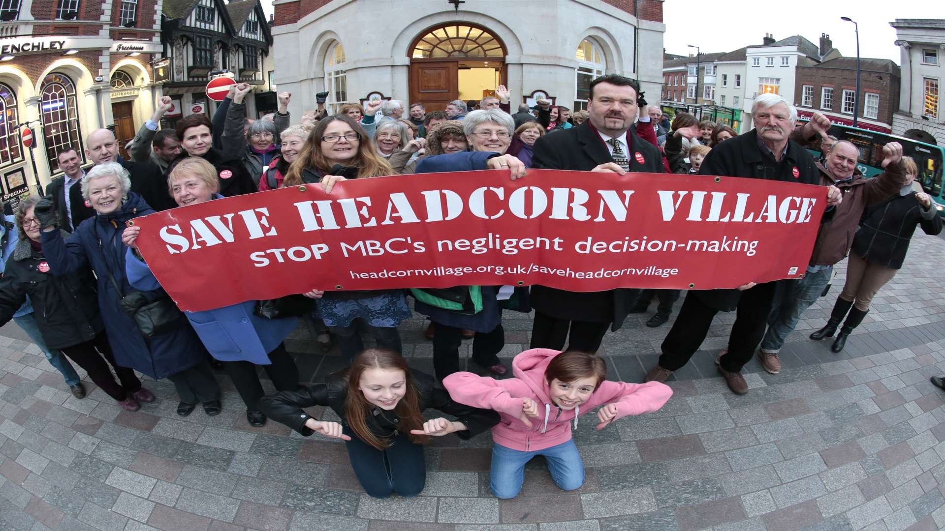 Protesters gather outside with banners against the building development in Headcorn