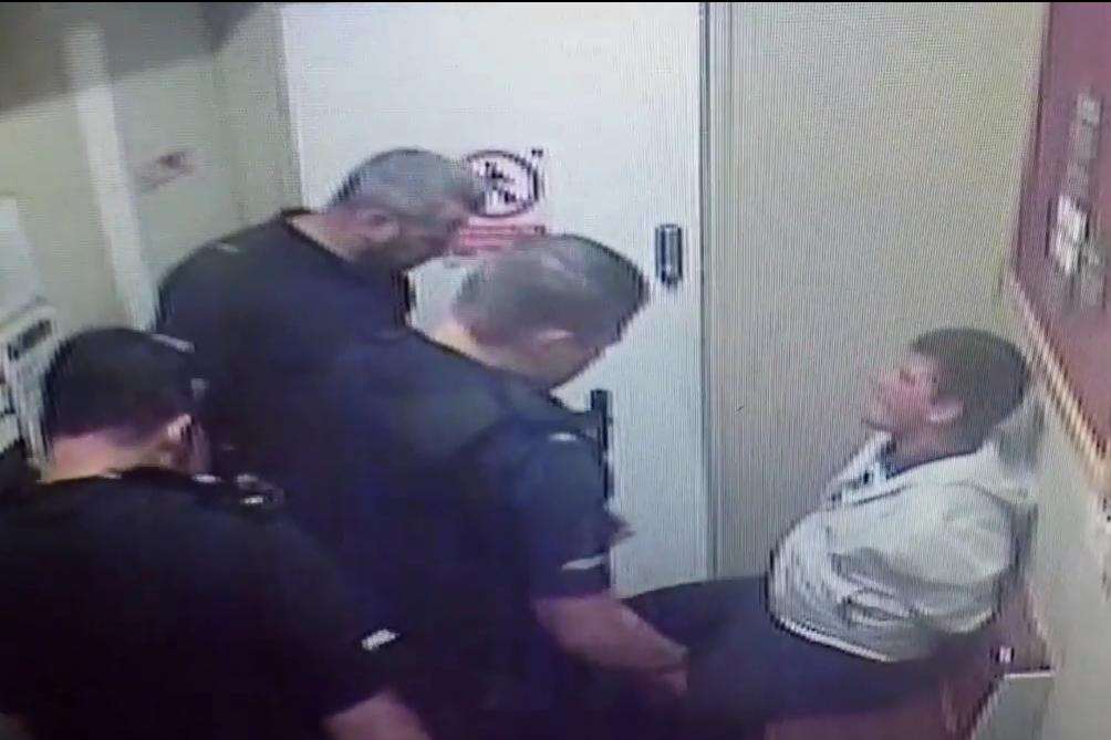 The footage ends with the suspect sitting while the officers talk to him