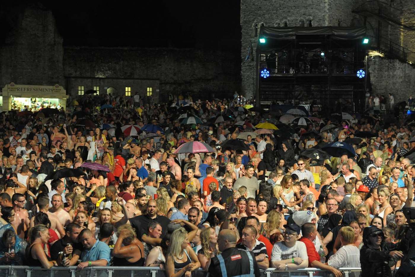 Crowds try to shelter from the rain during UB40's performance