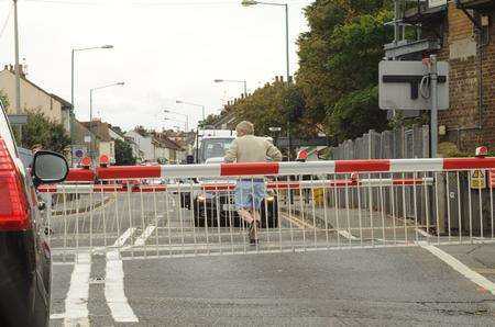 Man runs across tracks at level crossing as high-speed train approaches.