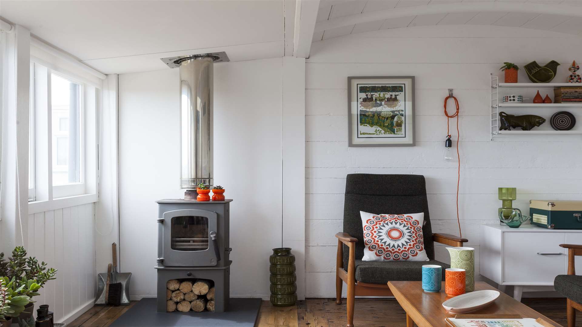 The living room sits within the original railway carriage and the space had been divided into two rooms. At night, beams from the nearby lighthouse flash across the room and a wood burner keeps the place warm.