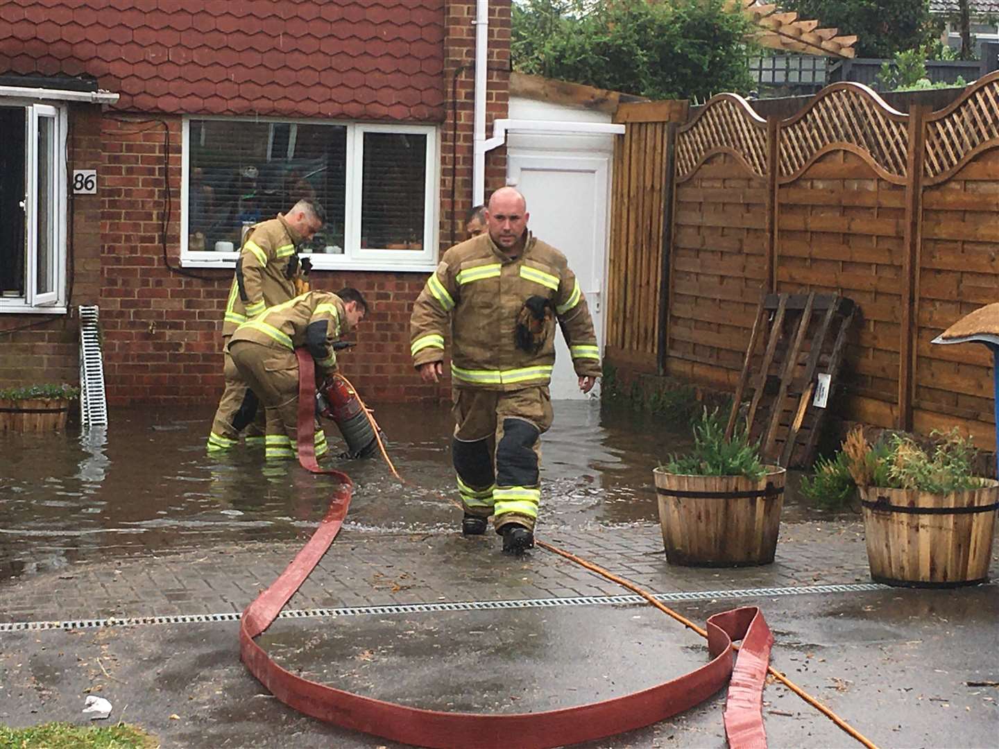 Firefighters pump out water from a flooded house in Coombe Drive, Murston, on Saturday Picture: John Nurden
