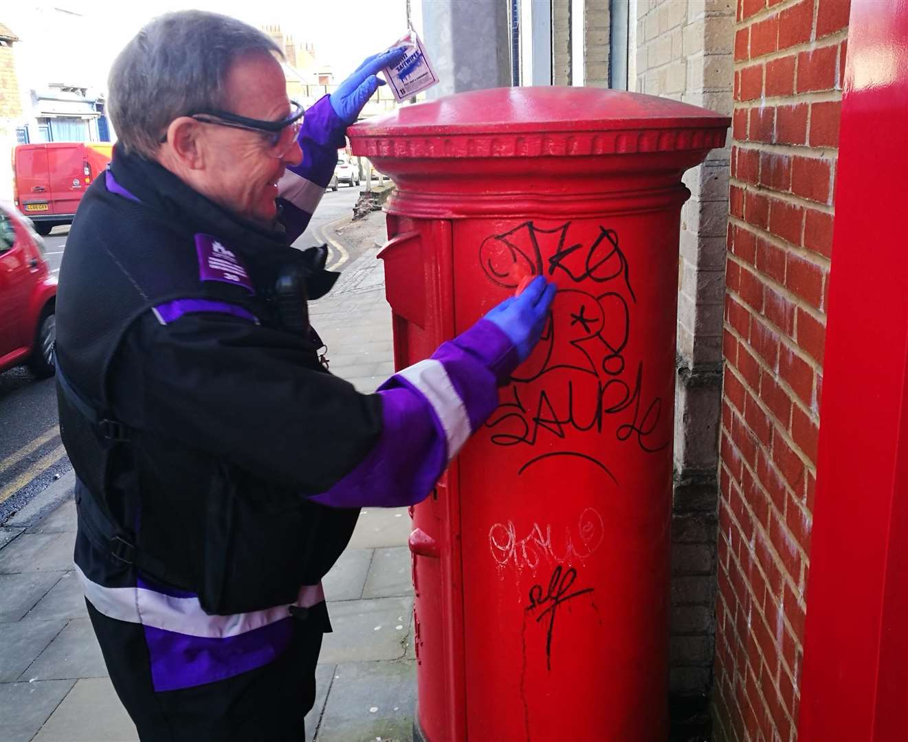 A council enforcement officer cleans tagging off a post pox