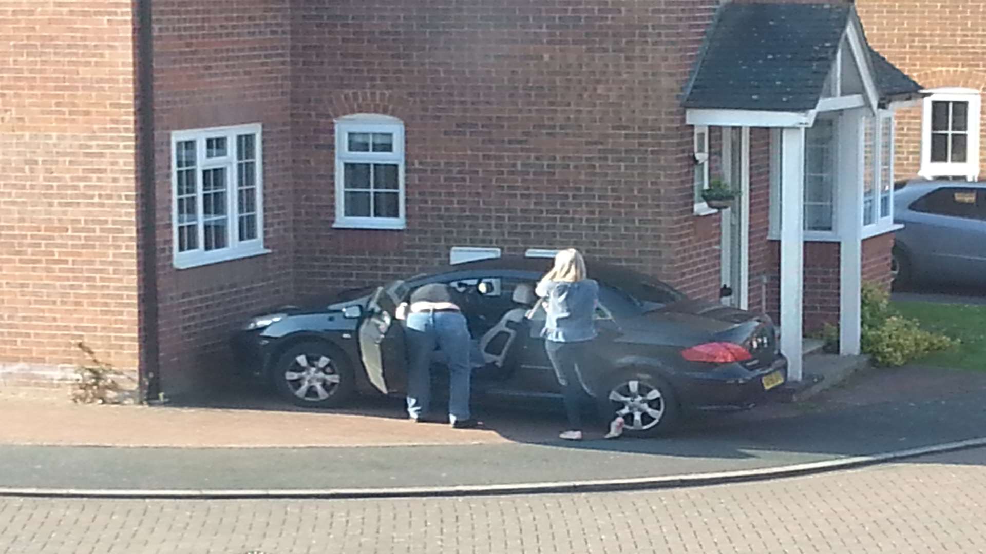 Police search a car owned by the occupants of the house