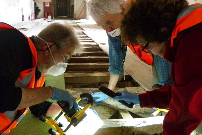 Archaeology volunteers investigate under the floorboards