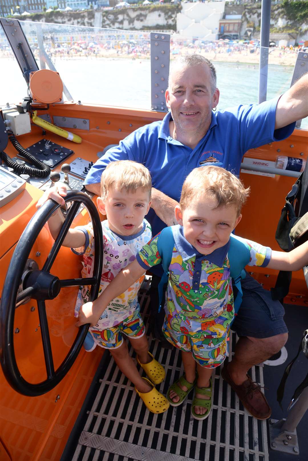 Flynn and Lewis Stuart, both five take the wheel of the Ramsgate Lifeboat with Lifeboat Mechanic Phil Mace at the Broadstairs Water Gala on Wednesday. Picture: Chris Davey. (3399820)