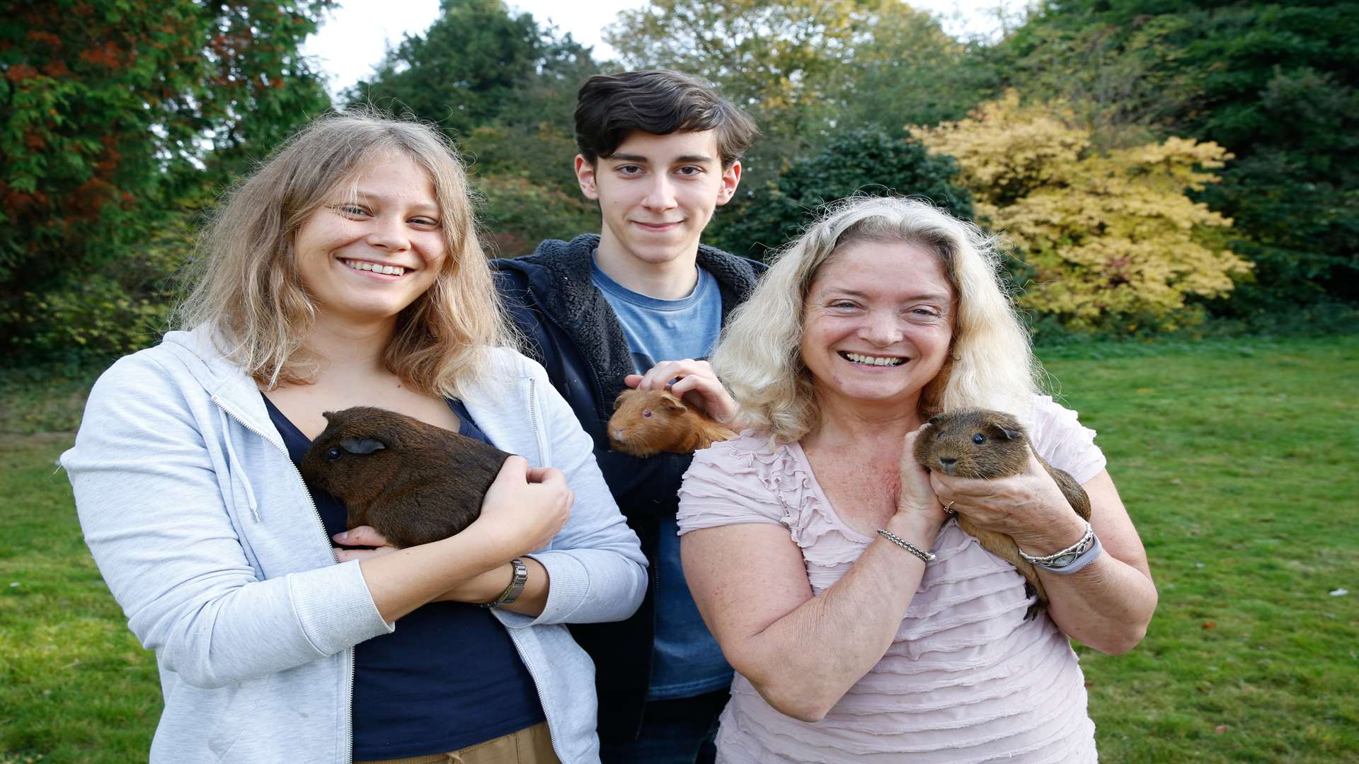 From left, volunteers Imke Dreyer and Johannes Lampe and lead therapist Carol Bridges cuddles the guinea pigs, which helps calm the children. Picture: Matthew Walker