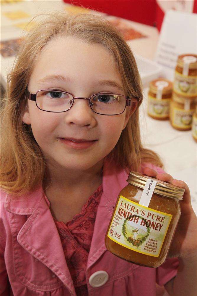 Seven-year-old bee-keeper Laura Marolia with a jar of her honey