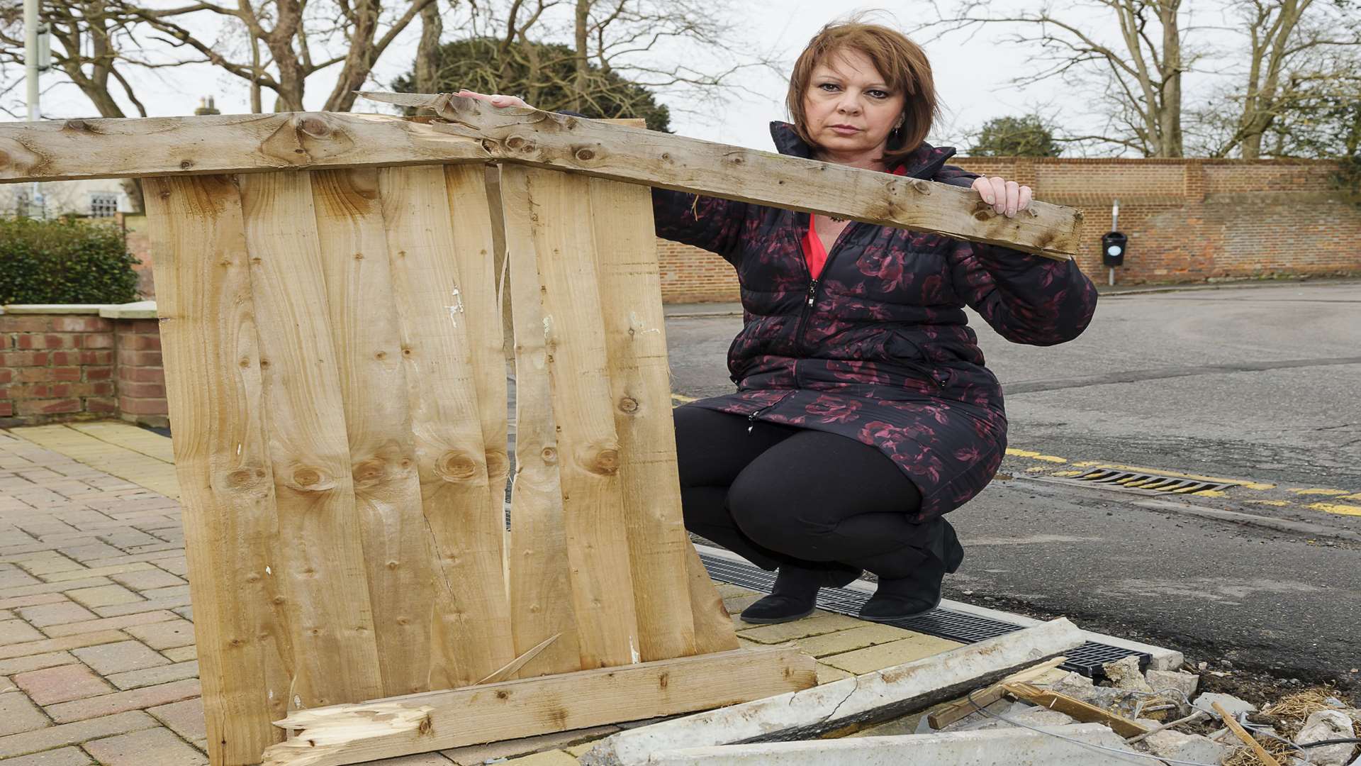 Suzanne Mayes with the damaged fencing outside her home