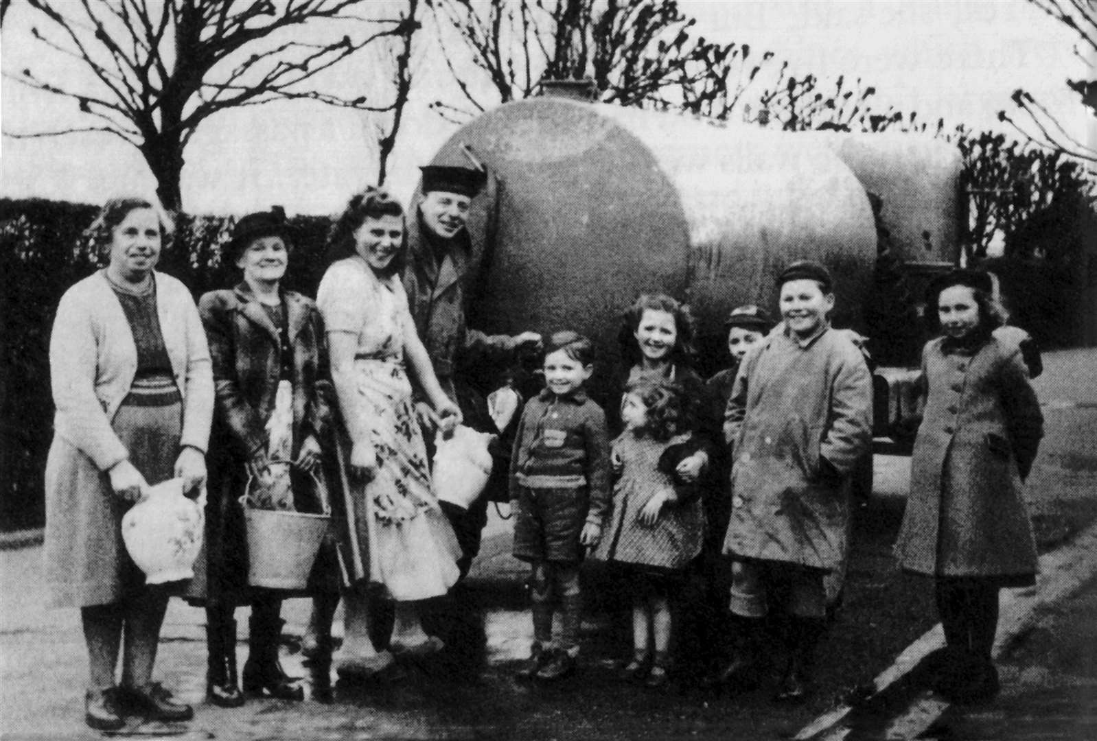 Women and children queue for fresh water from a bowser in Beach Street, Sheerness, after the flood