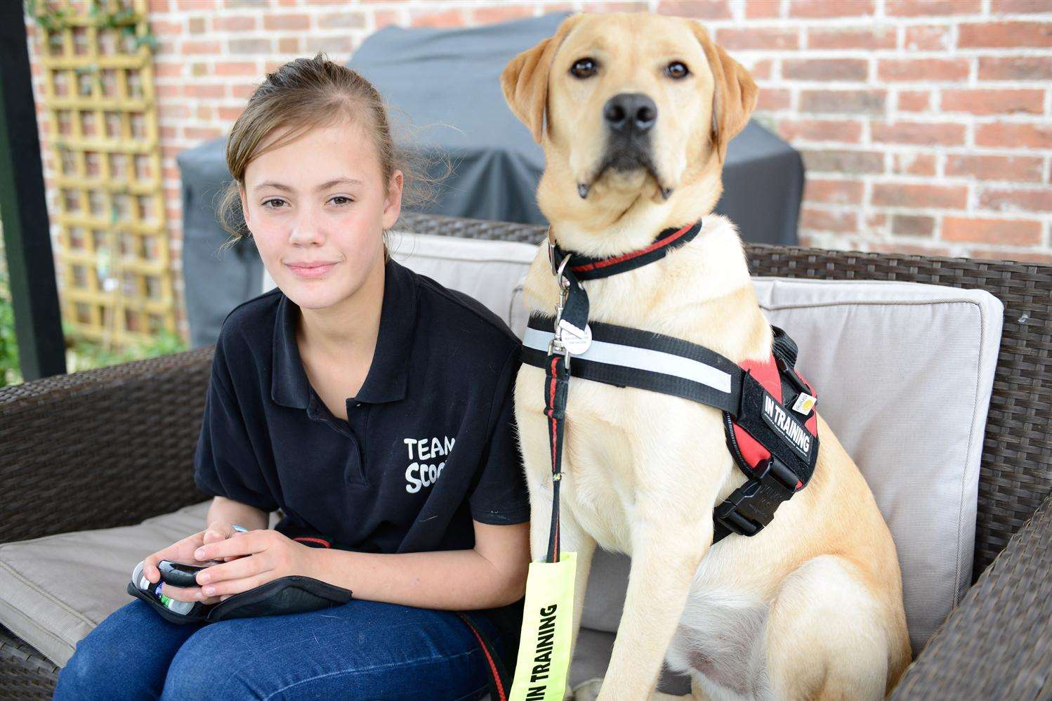 Sophie-Alice Pearman, 11, checks her sugar levels with Scooby her medical assistance dog.