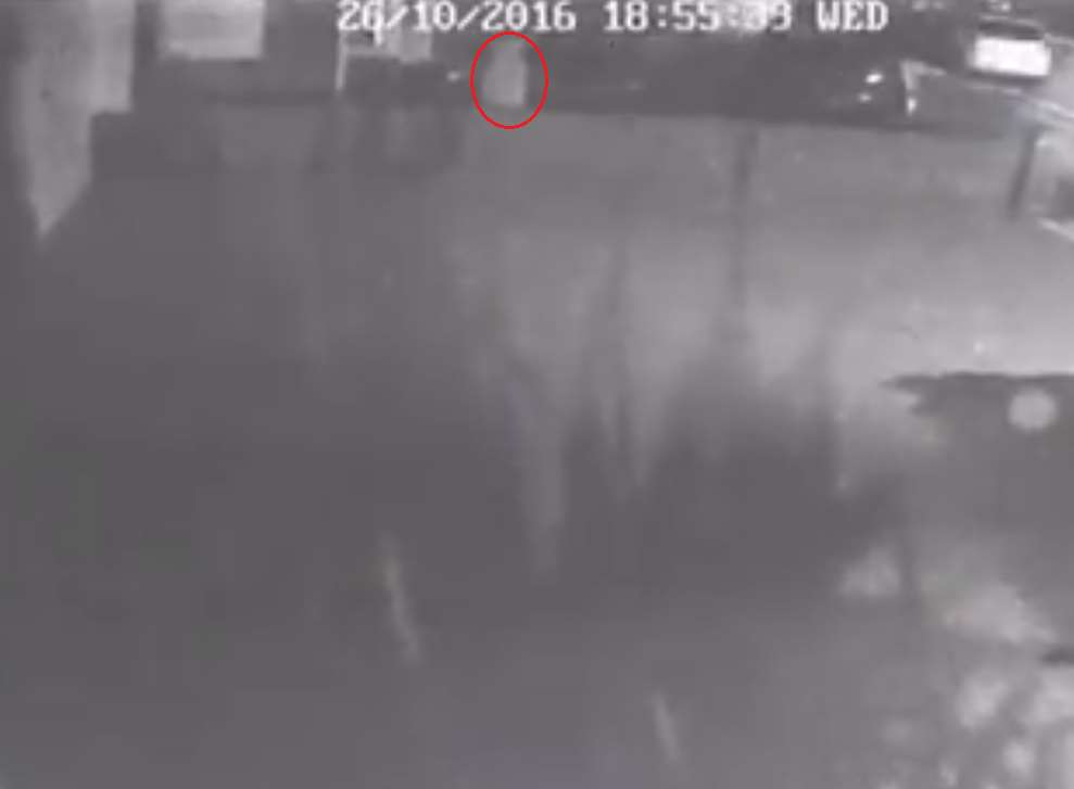 The CCTV shows the rough outline of a person going up the alleyway before climbing over the low wall.