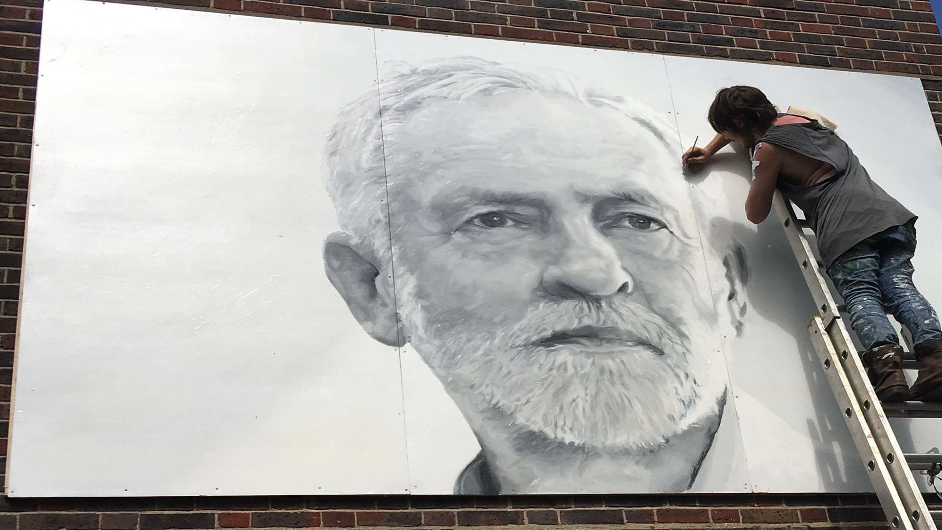 Artist Sam Collins painting a giant mural of Jeremy Corbyn on the side of a London pub