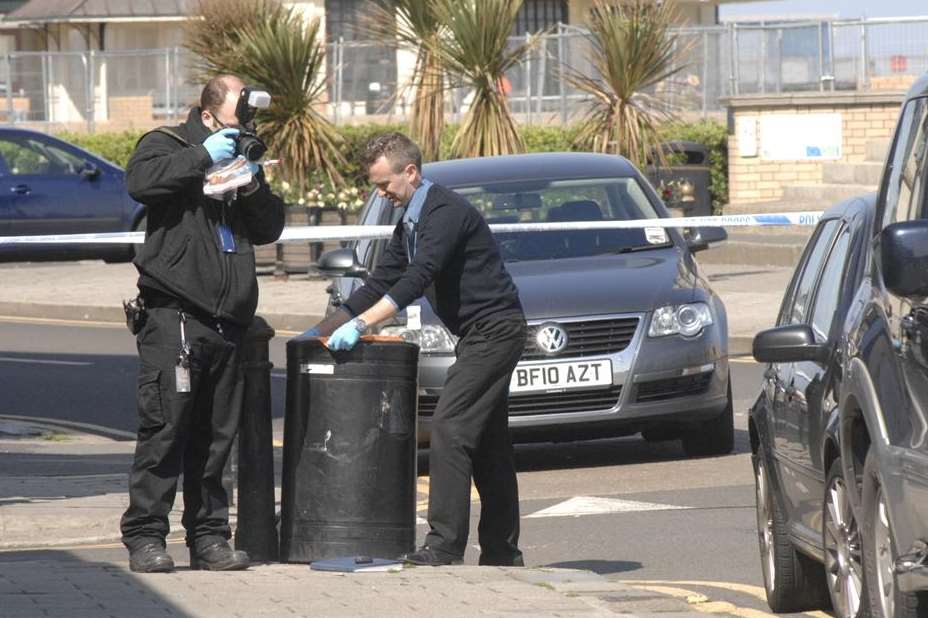 Officers search nearby bins for a weapon