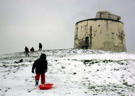Sledgers tredge up a hill to a Martello tower in Folkestone