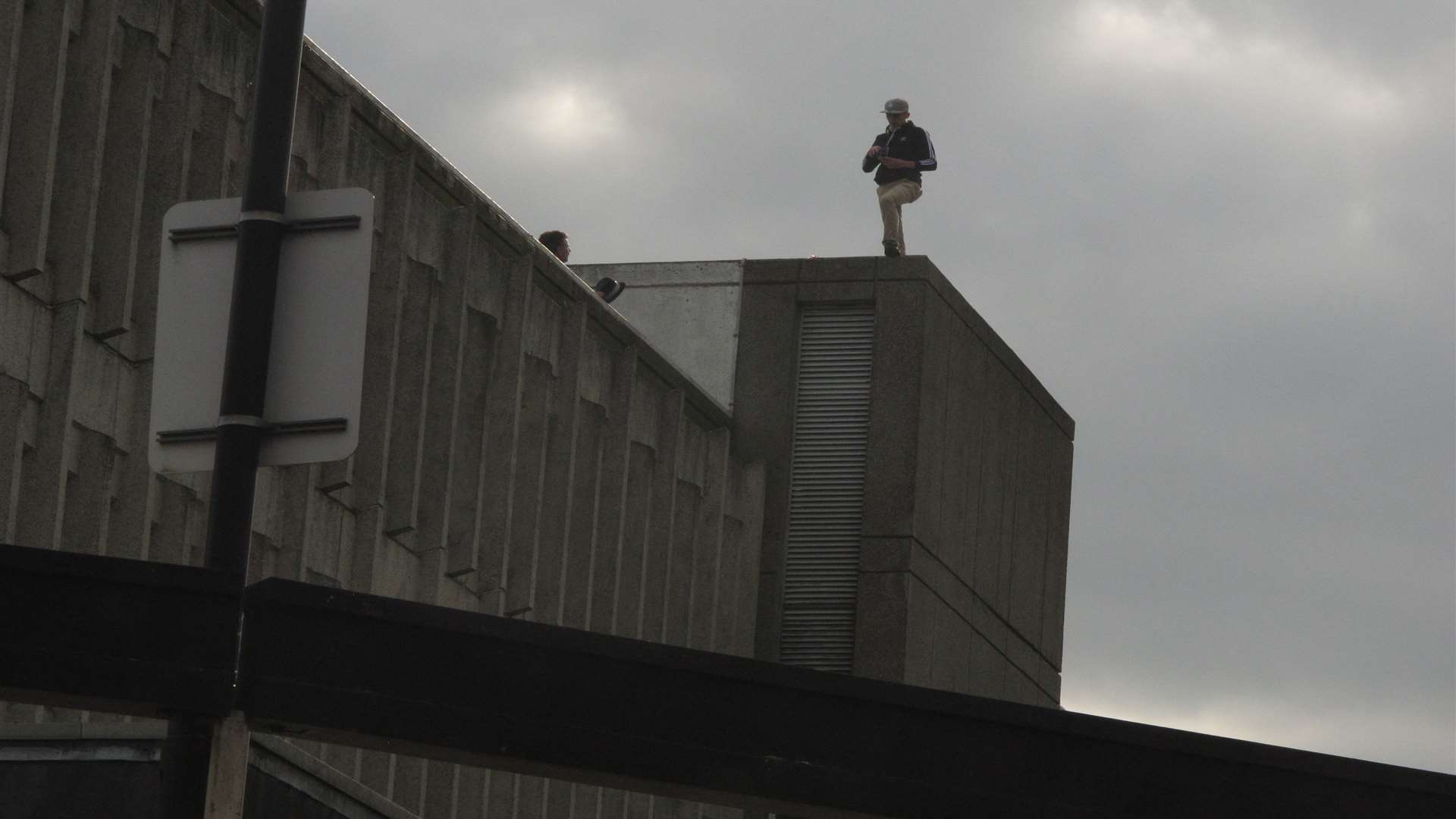 Officers are talking to the man who is on the roof or a multi-storey carpark