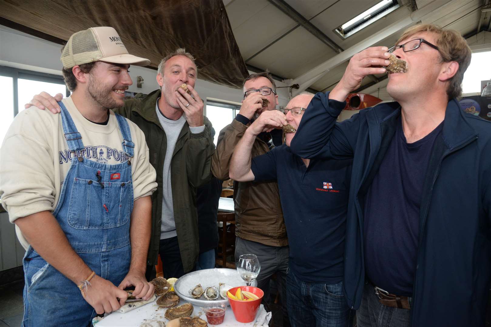 William Green opens oysters whilst Gus Corcoran of the Whitstable Oyster Festival, Robin Moxon and Paul Earles of Moxon Fresh Fish and Francis Lucey purification manager at at the Whitstable Oyster Fishery Company sample them at The Lobster Shack
