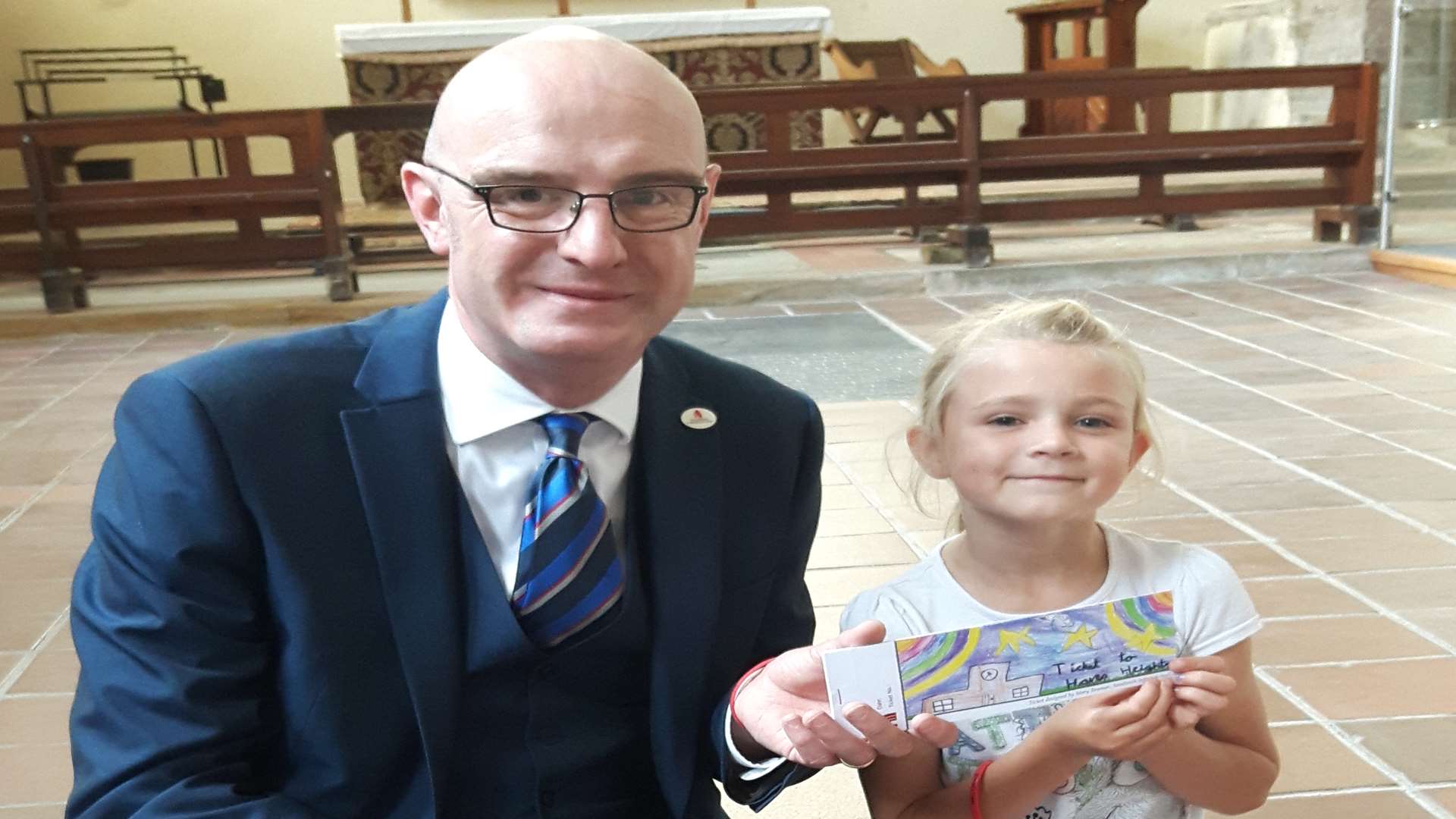 Peter Aiers, a director of the CCT, with seven-year-old Mary Beaman who designed the tour ticket