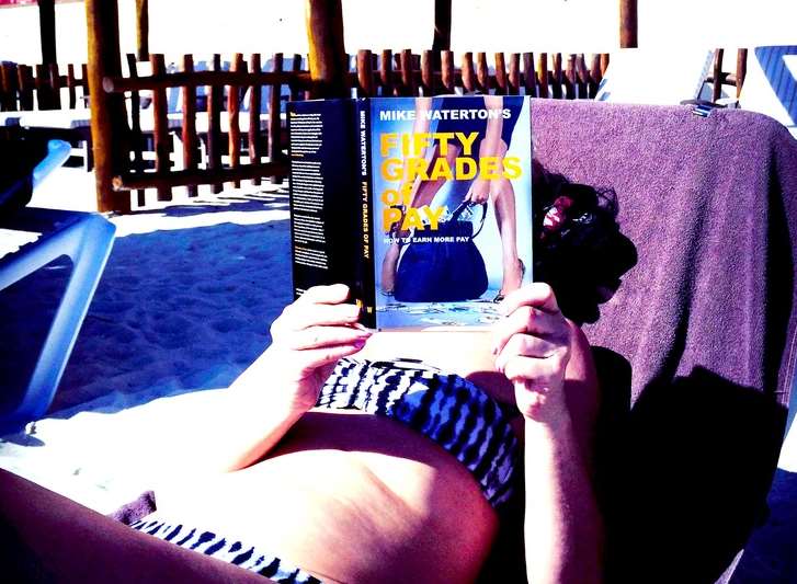 A bikini-clad woman holding one of Mike Waterton's books in Cancun
