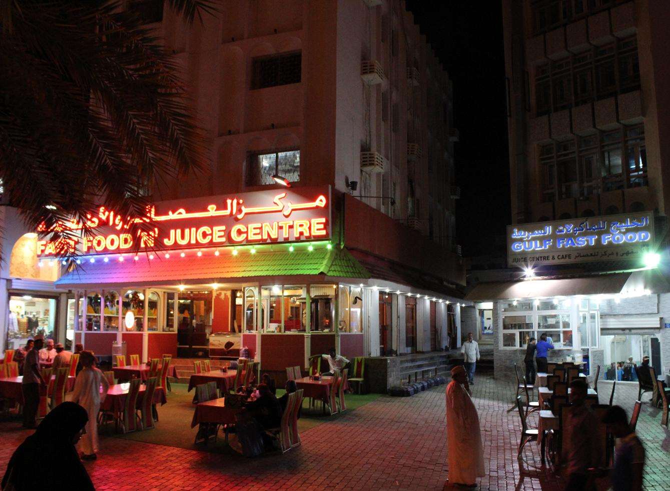 Fast food stores illuminate a market square in Muscat, Oman. Picture: Ed McConnell