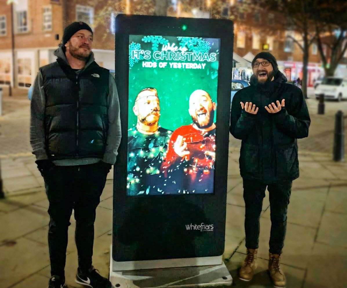 (Left to right) Musicians Stuart Weller and James O'Keeffe with an advert for their Christmas song in Canterbury city centre. Picture: Stuart Weller