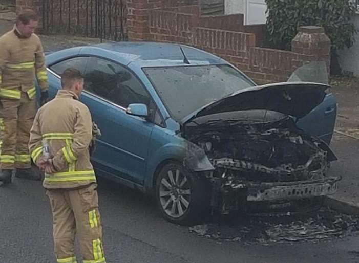 Gutted: Firemen check the remains on the car in Seaside Avenue