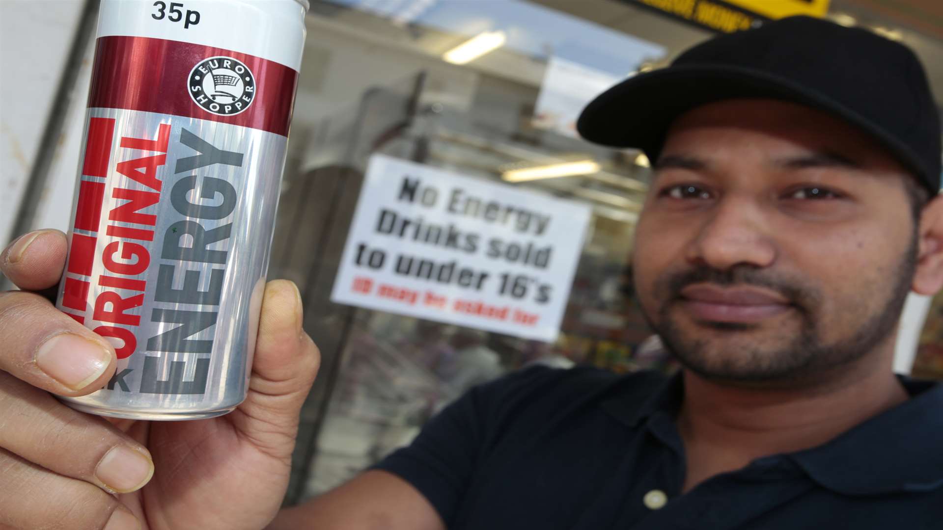 Newsagent manager Jahangir Alam by the sign he has put up about not selling energy drinks to under 16s