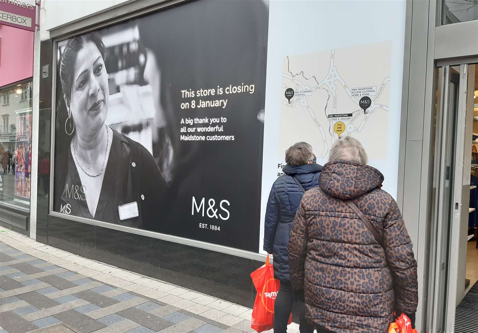 Shoppers stop to read a sign announcing the closure of the M&S store in Week Street, Maidstone