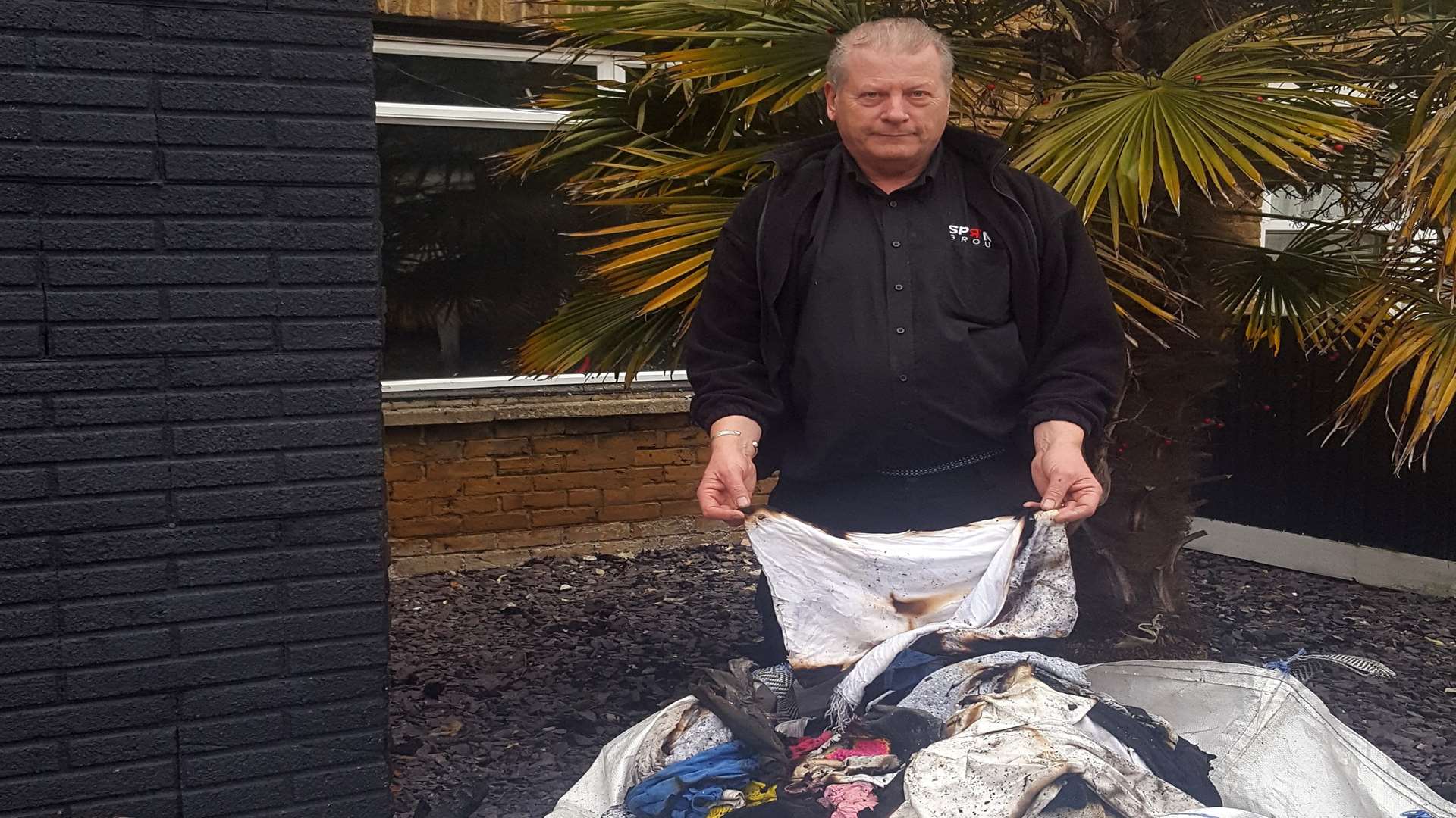 Keith Plews sorts through charred clothing outside his home
