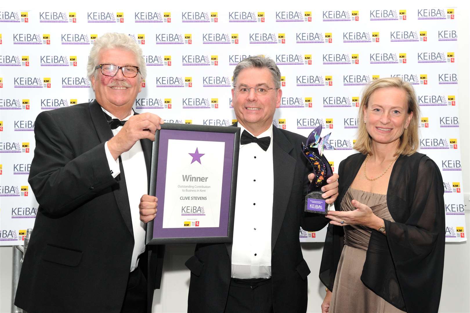 Kent County Council's Mark Dance and KM Media Group chairman Geraldine Allinson present Clive Stevens, centre, with his outstanding contribution to Kent business at 2018's event