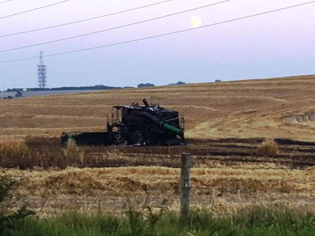 The wrecked combine harvester sits forlornly in a field