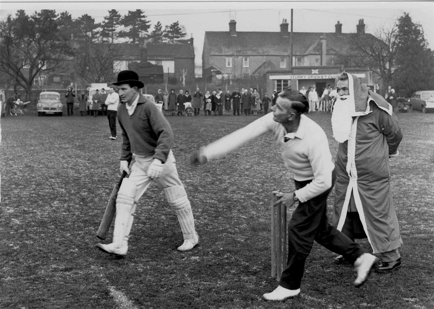 Father Christmas (umpire Sid Burton) watches J Worrell on his way to take six wickets for Sturry, as Canterbury Choughs batsman Malcolm Longley looks on in 1965. The Boxing Day cricket match at Sturry was in aid of the League of Friends of Canterbury Hospitals