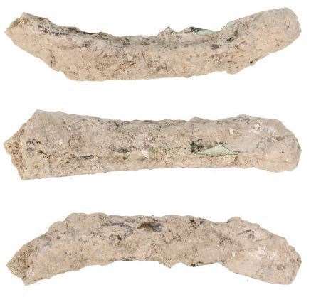 A bone fragment, probably a human rib, with embedded copper alloy fragment