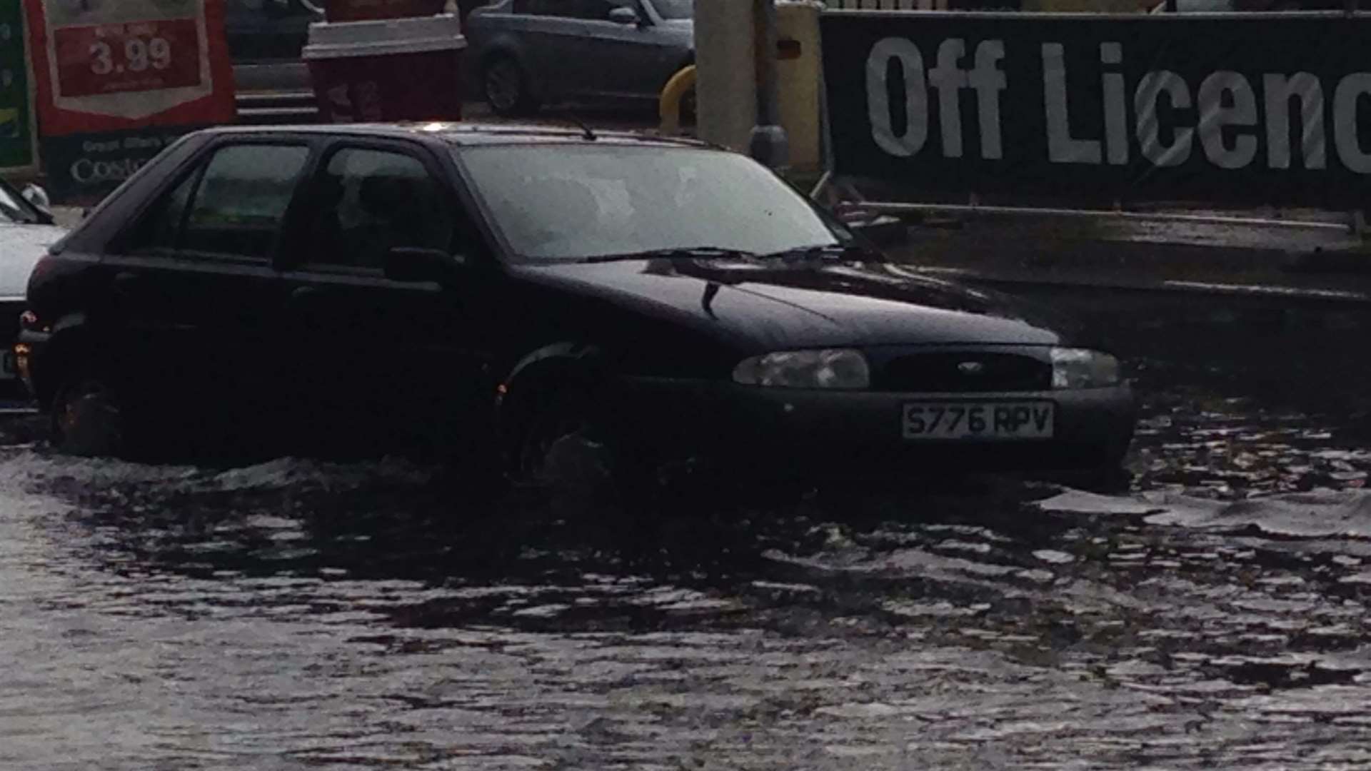 A parked car up to its wheels in floodwater in New Romney High Street.