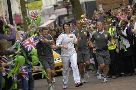 Torchbearer Lynne Oliver carries the flame in Ashford town centre. Picture: Gary Browne