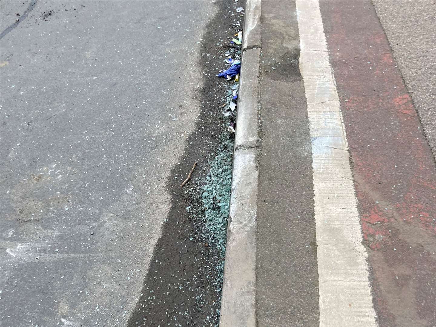 Smashed glass next to the kerb, possibly from the accident