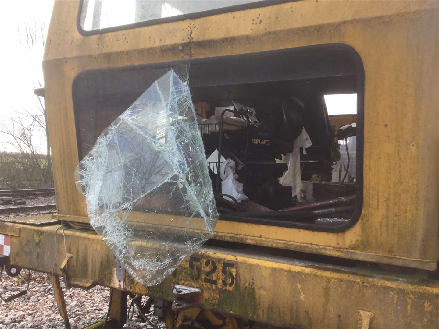 Damage to the tamping machine where glass covered by plastic was smashed to gain entry to the cab above