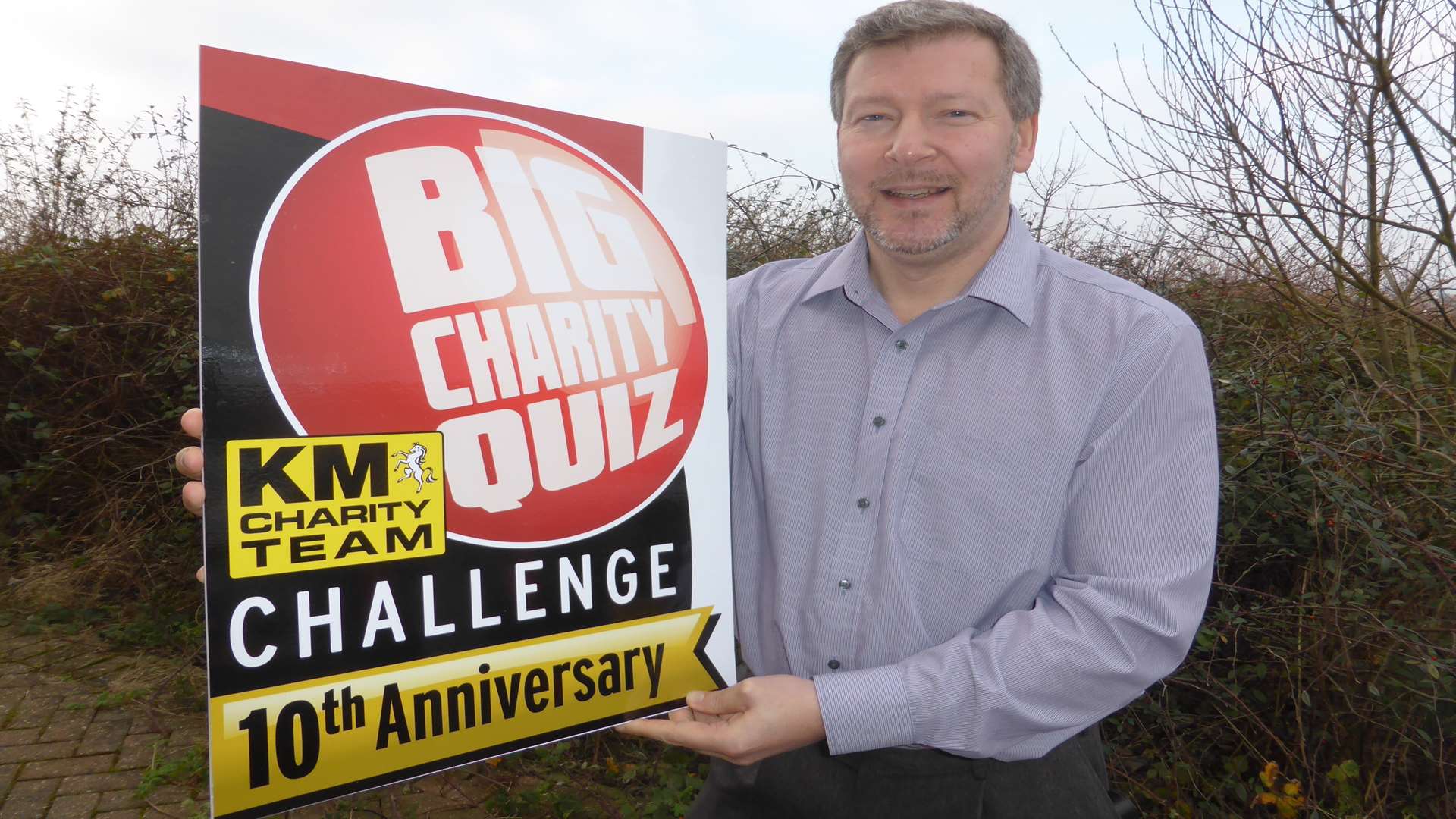 Quizmaster Simon Dolby shows off the new anniversary logo for the KM Big Charity Quiz.