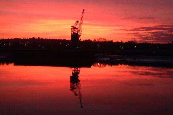 A perfect reflection of a crane in the River Medway during a brilliant red sunset over Rochester