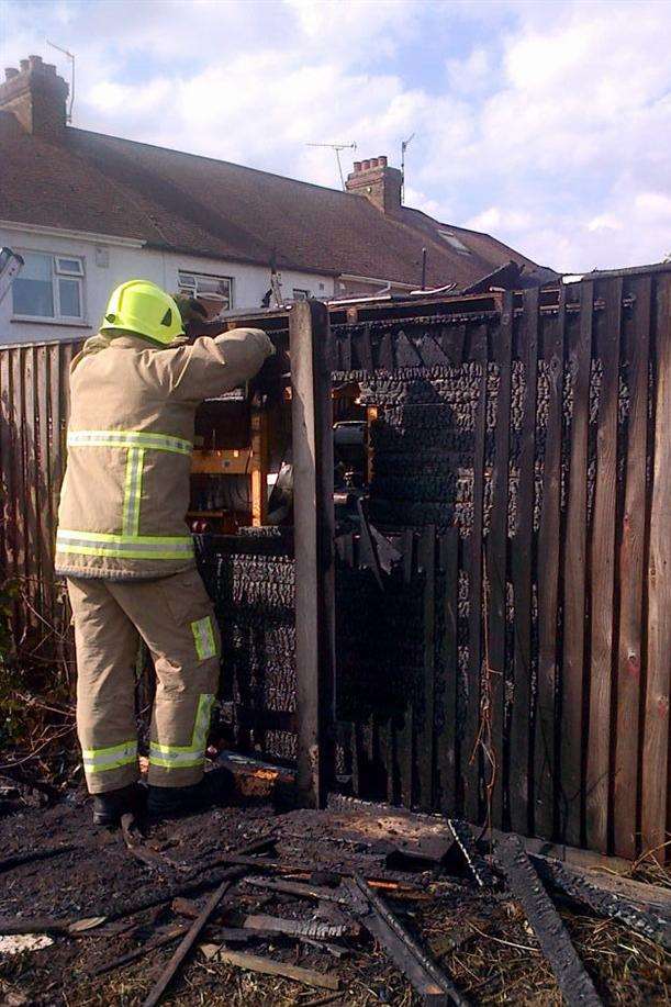 A fireman surveys the damage to the fence and shed in the rear garden of a house in Abbey Road, Gravesend. Picture by Amy Roberts.