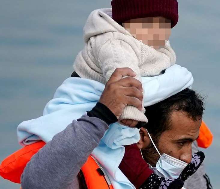 A man carrying a baby wrapped in blanket was among a group who were brought ashore in Kent on Friday (Gareth Fuller/PA)