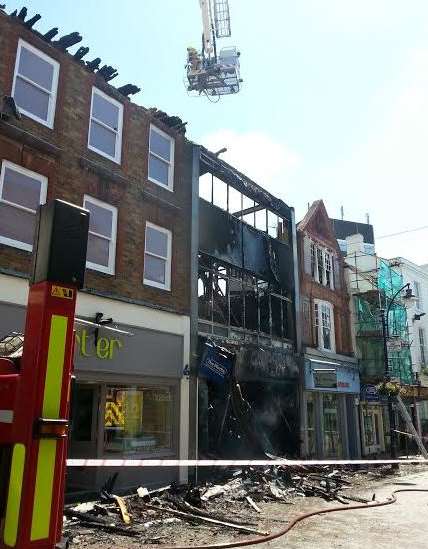 Firefighters in a cherry picker survey the damage to The Works book store