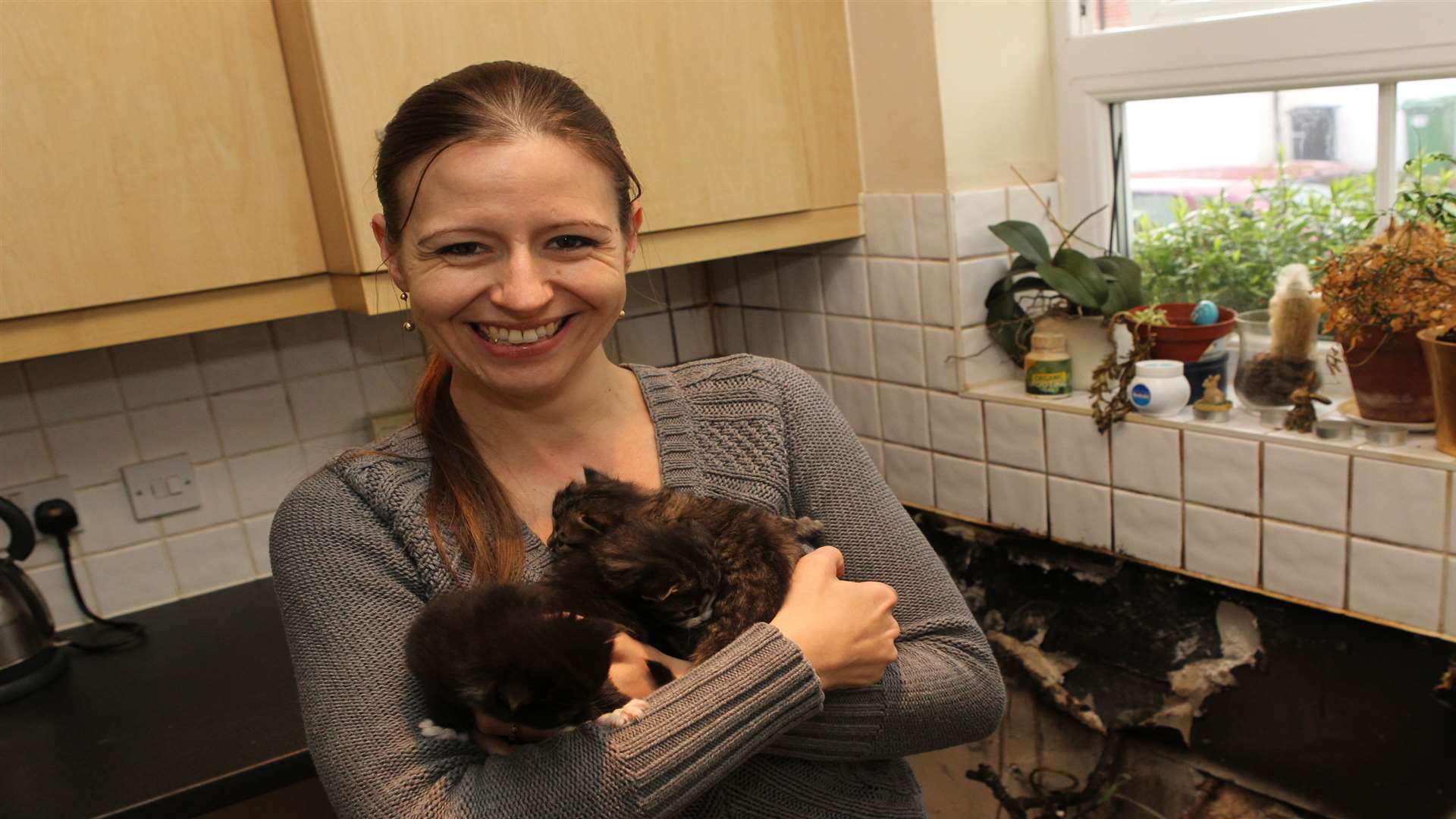 Tay Arnold holds her three-week-old kittens in her fire damaged kitchen